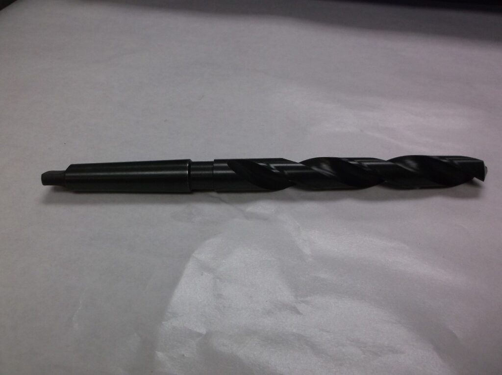 A close-up of a taper shank drill bit with a conical shank, designed for secure fit in drill press spindles.